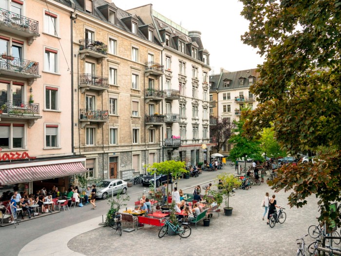 People eating at tables on Idaplatz and on a shaded terrace in front of a restaurant