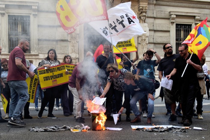 People burn electricty bills and carry  banners during a protest in Italy