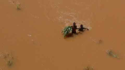People wade through flood waters after heavy rain in Garsen, east Kenya