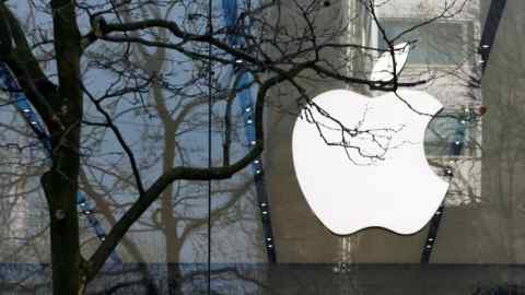 The Apple logo inside a building, seen through the branches of a tree
