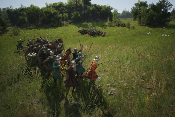In an image from a video game, two groups of archers in medieval armour stand in open countryside, firing arrows