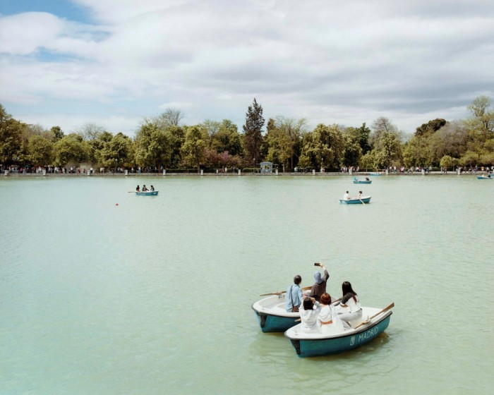 Blue rowing boats on the lake in El Retiro, with trees lining the bank in the distance