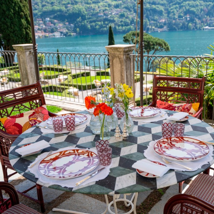 A table set for a meal on a terrace overlooking a lake 