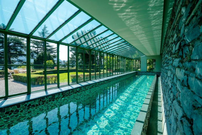 A swimming pool with mosaic floor, with windows looking on to formal gardens