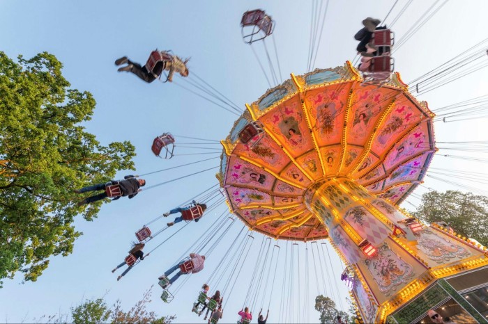 Frankfurt’s Forest Day festival is centuries-old People swirling high above the ground on a fairground ride at Frankfurt’s Forest Day against a blue sky and with the top of a tree to the left of the image 