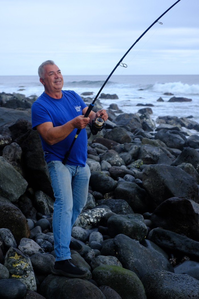 A man in blue shirt and jeans casting his fishing rod