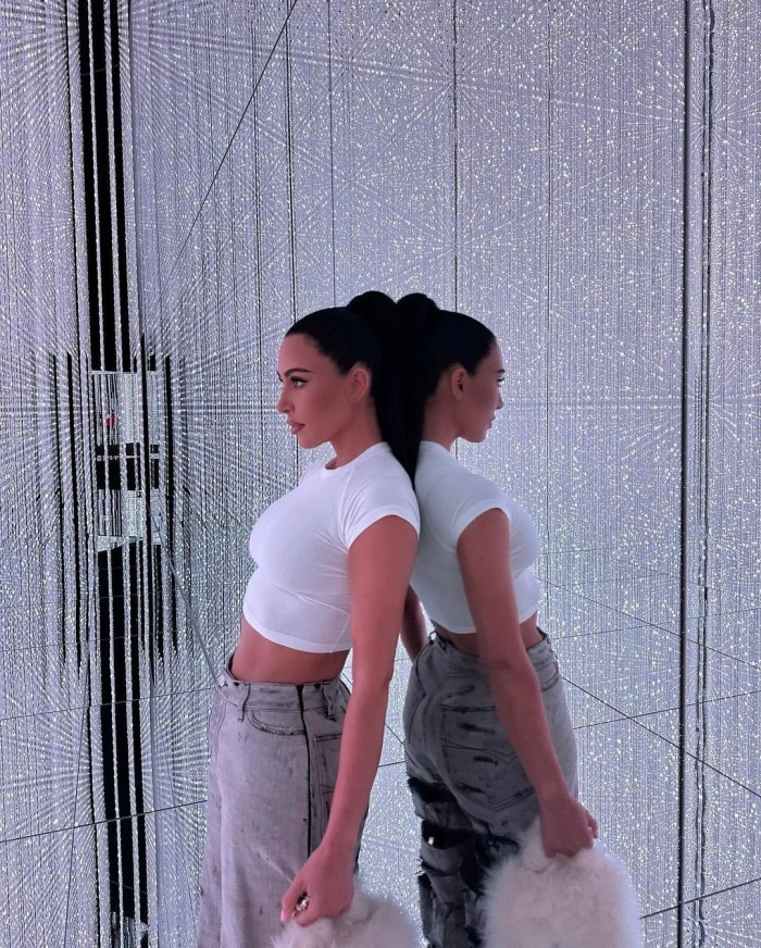 Kim Kardashian leaning back against a mirrored wall in a room full of silver LED lights at teamLab Planets