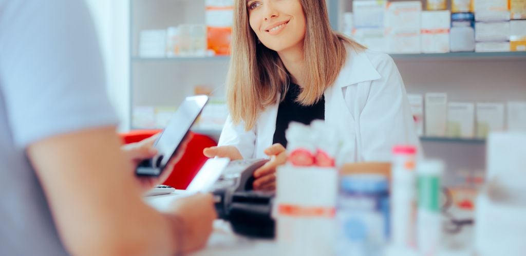 pharmacist checking prescription drugs with purchaser across the counter 