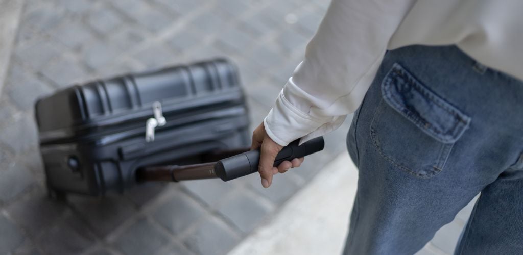 traveller rolling a suitcase behind her with white blouse and jean pants