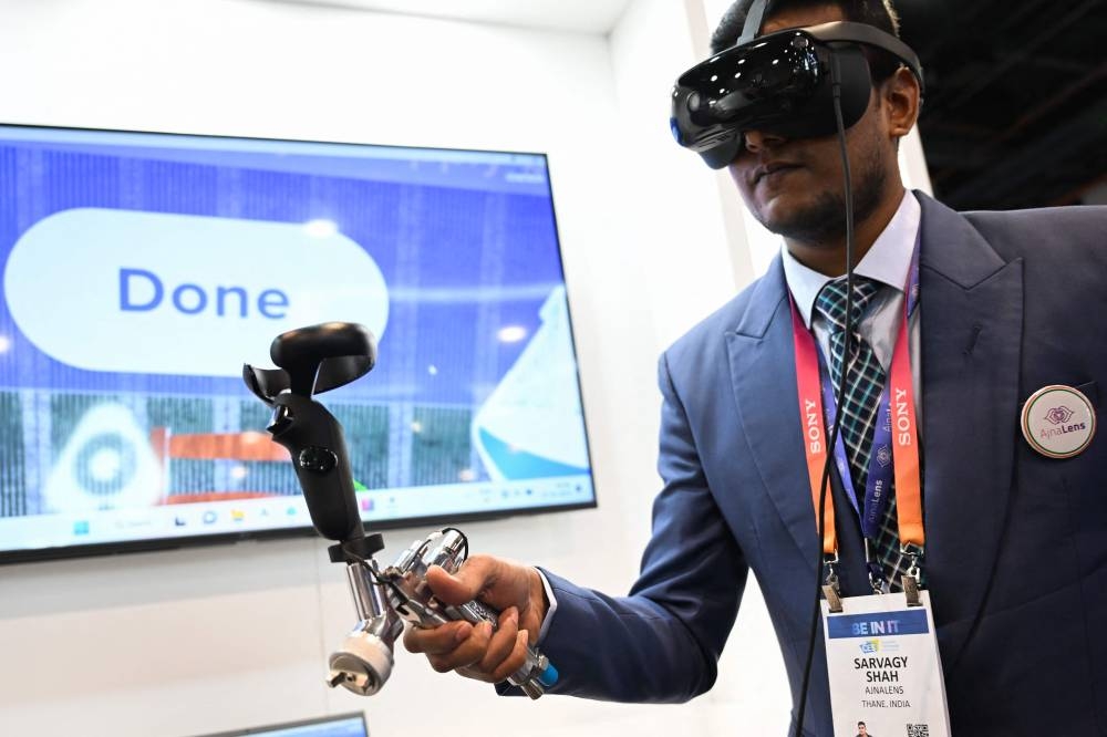 The AjnaXR mixed-reality system for augmented reality (AR) and virtual reality (VR) training is demonstrated with a paint sprayer at the AjnaLens company booth during the Consumer Electronics Show (CES) in Las Vegas, Nevada, on January 6, 2023. — AFP pic