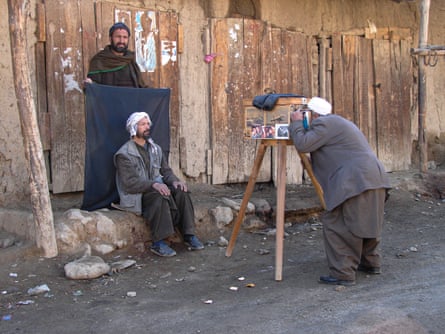 A man has a portrait taken by a photographer with a box camera