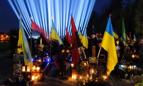 A commemoration event takes place at the Lychakiv military cemetery in Lviv, Ukraine, where family members visit the graves of fallen soldiers.