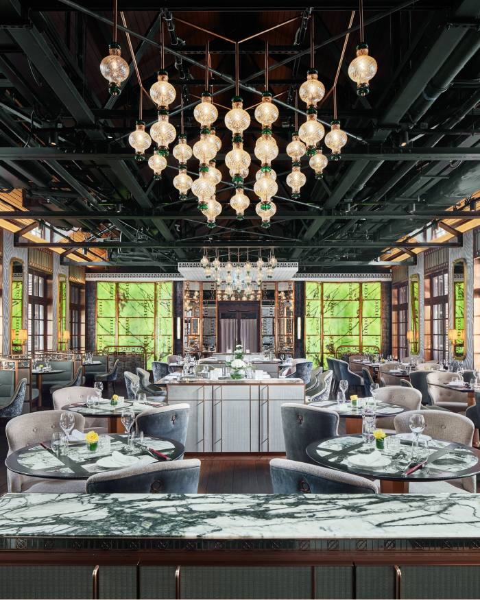 The ornate interior of The Chinese Library restaurant, with marble-topped counters and tables and clusters of globe lamps hanging from the ceiling