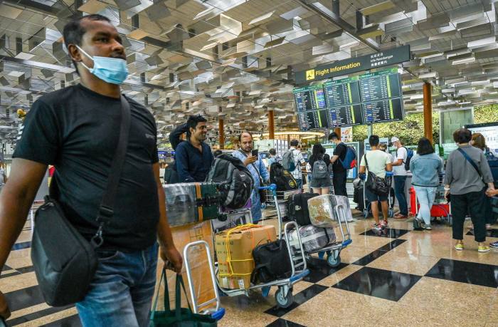 Travellers queue to check-in for their flight departure at Singapore Changi airport