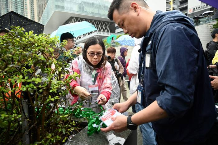 A Hong Kong police officer issues numbered lanyards to protesters at the first authorised demonstration in several years, against a land reclamation project, in March