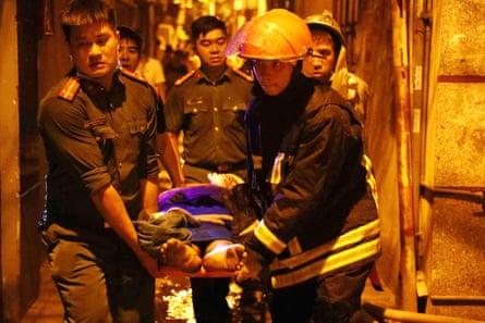 Rescue workers carry victims after a major fire at an apartment block in Hanoi