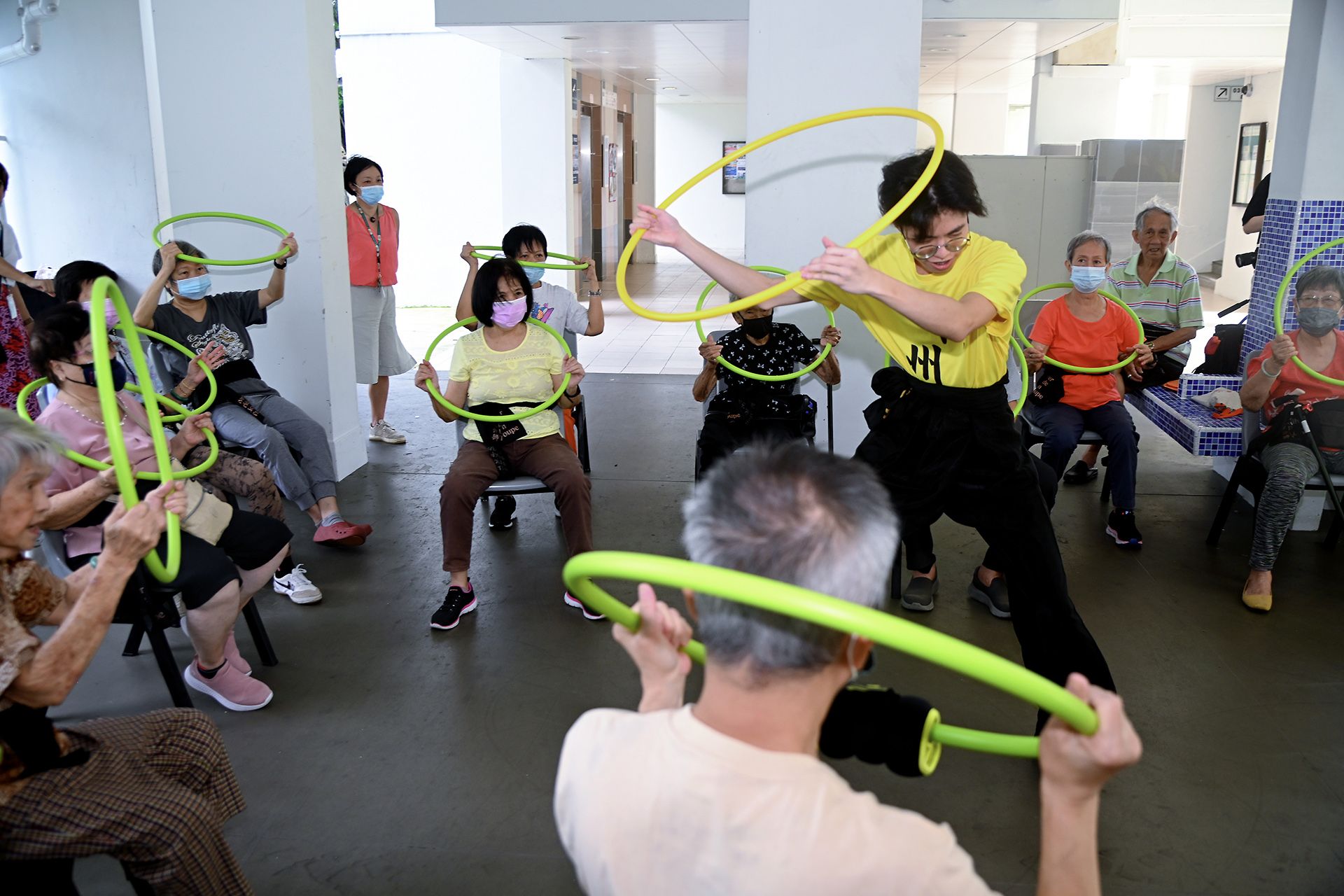 Kong Chow Wui Koon lion dance troupe member Lucas Ow, 16, leading seniors in a series of lion dance moves using a hula hoop to simulate holding a lion head, outside Fei Yue Active Ageing Centre in Holland Close on Dec 29, 2023.