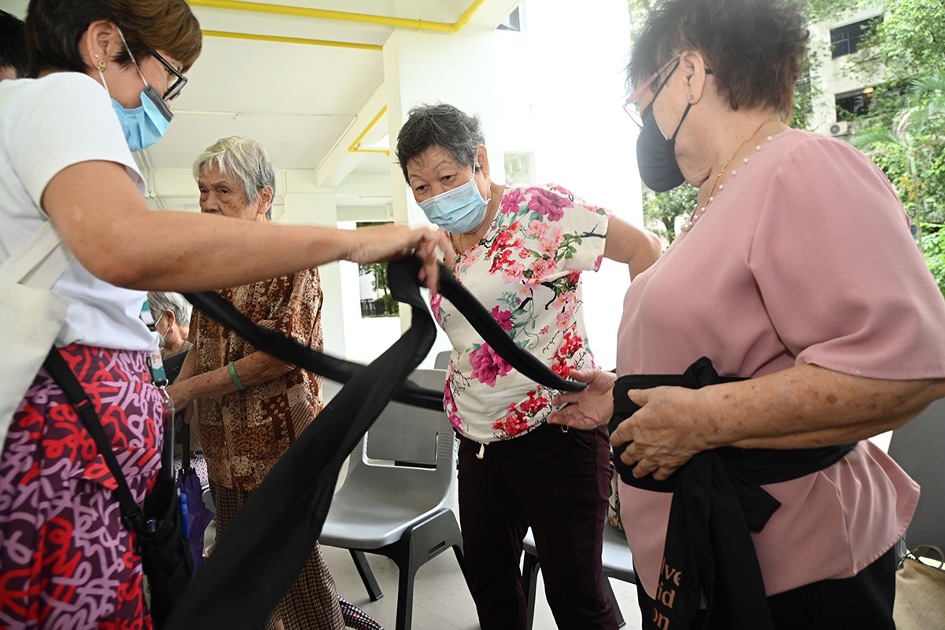 Madam Teo Poh Eng (centre) putting on a sash with the help of Ms Bo Chai Hiah during a practice session at Fei Yue Active Ageing Centre in Holland Close on Dec 29, 2023.