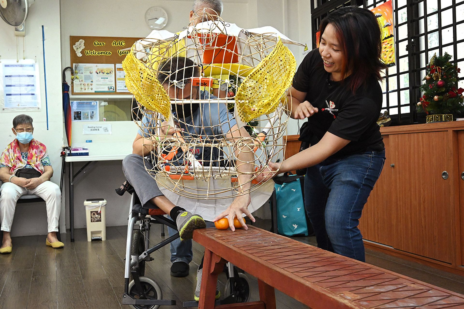Ms Lynn Wong guiding a senior in executing the "eating the green" lion dance movement.