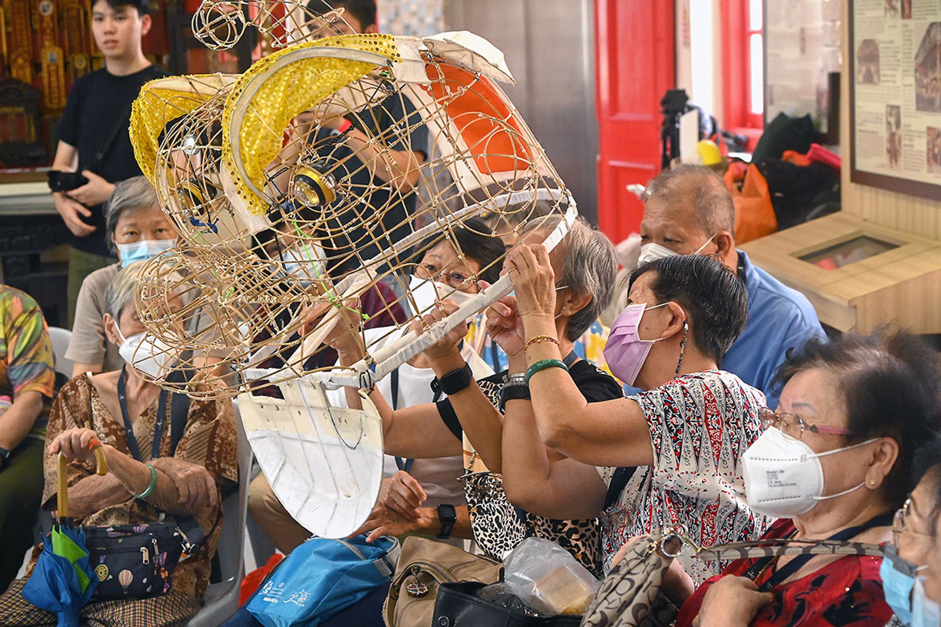 Seniors testing the lion head frames with add-on prototypes, designed by NextOfKin Creatives in consultation with Bridging Generations, during an excursion to Kong Chow Wui Koon on Dec 15, 2023.