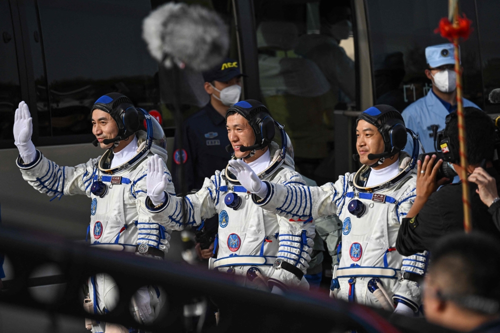 Astronauts for China's Shenzhou-18 space mission (from left) Ye Guangfu, Li Cong and Li Guangsu wave during a departure ceremony before boarding a bus to take them to the Shenzhou-18 spacecraft at the Jiuquan Satellite Launch Centre in the Gobi desert April 25, 2024. — AFP pic