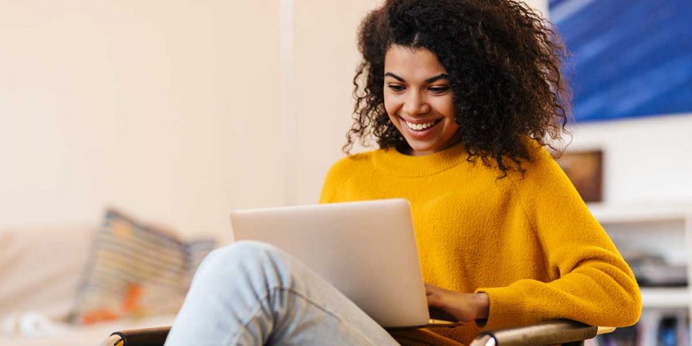 Black-woman-in-yellow-jumper-using-laptop