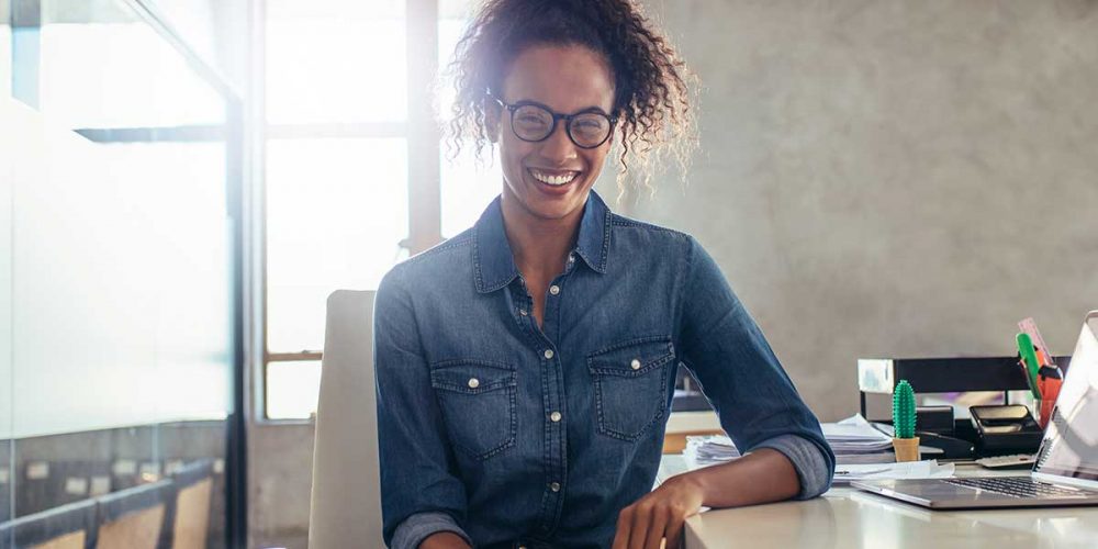 female-employee-smiles-at-the-camera-after-coding-emails