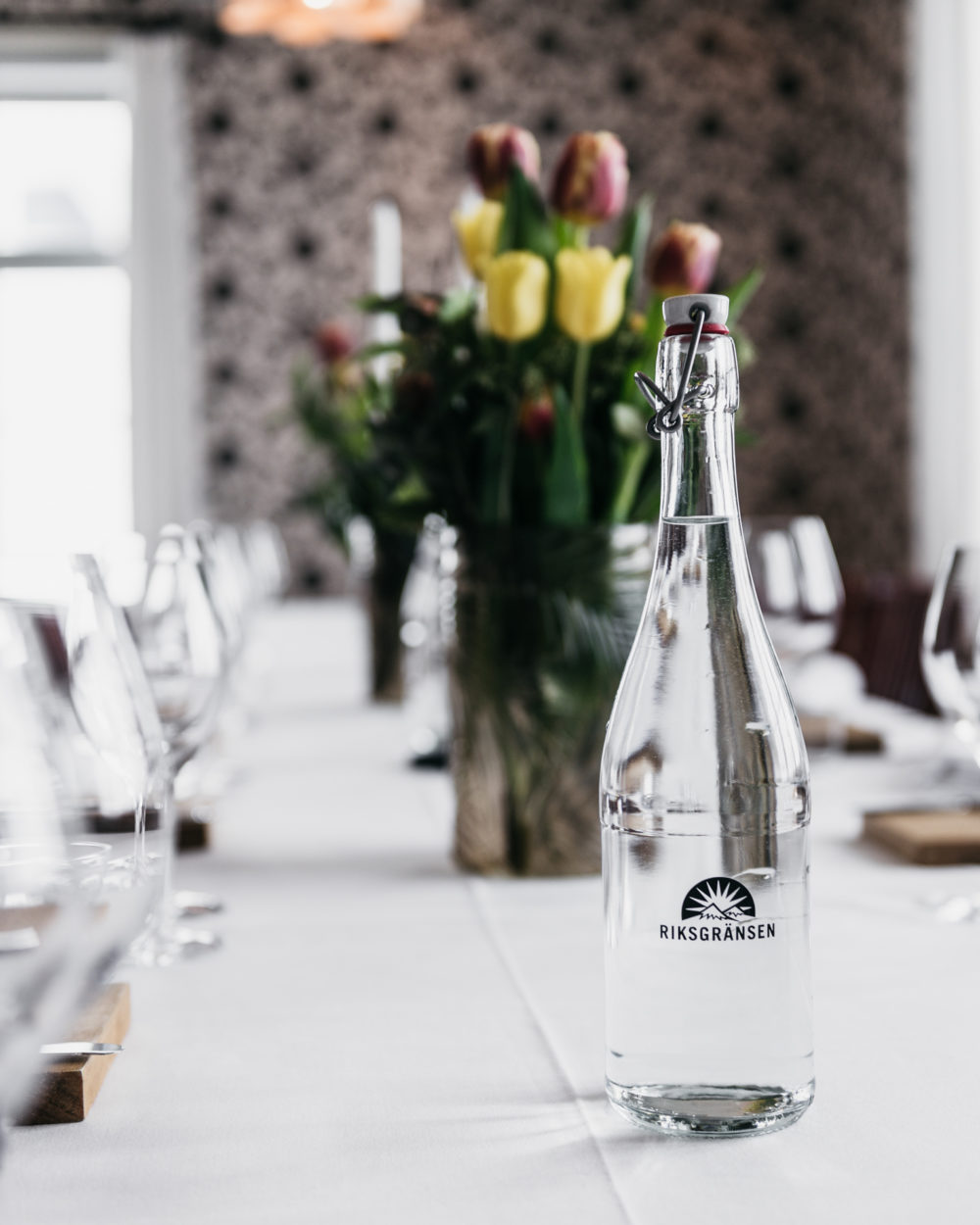A bottle of water sits on a table with wine glasses. Riksgränsen Björkliden.