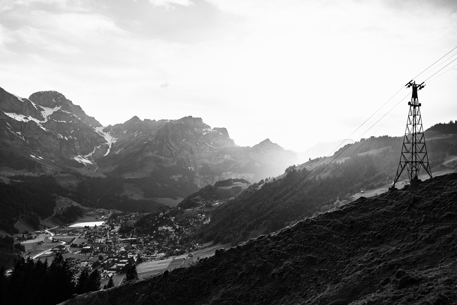 A black and white photo of a mountain with a power line in Engelberg Switzerland.