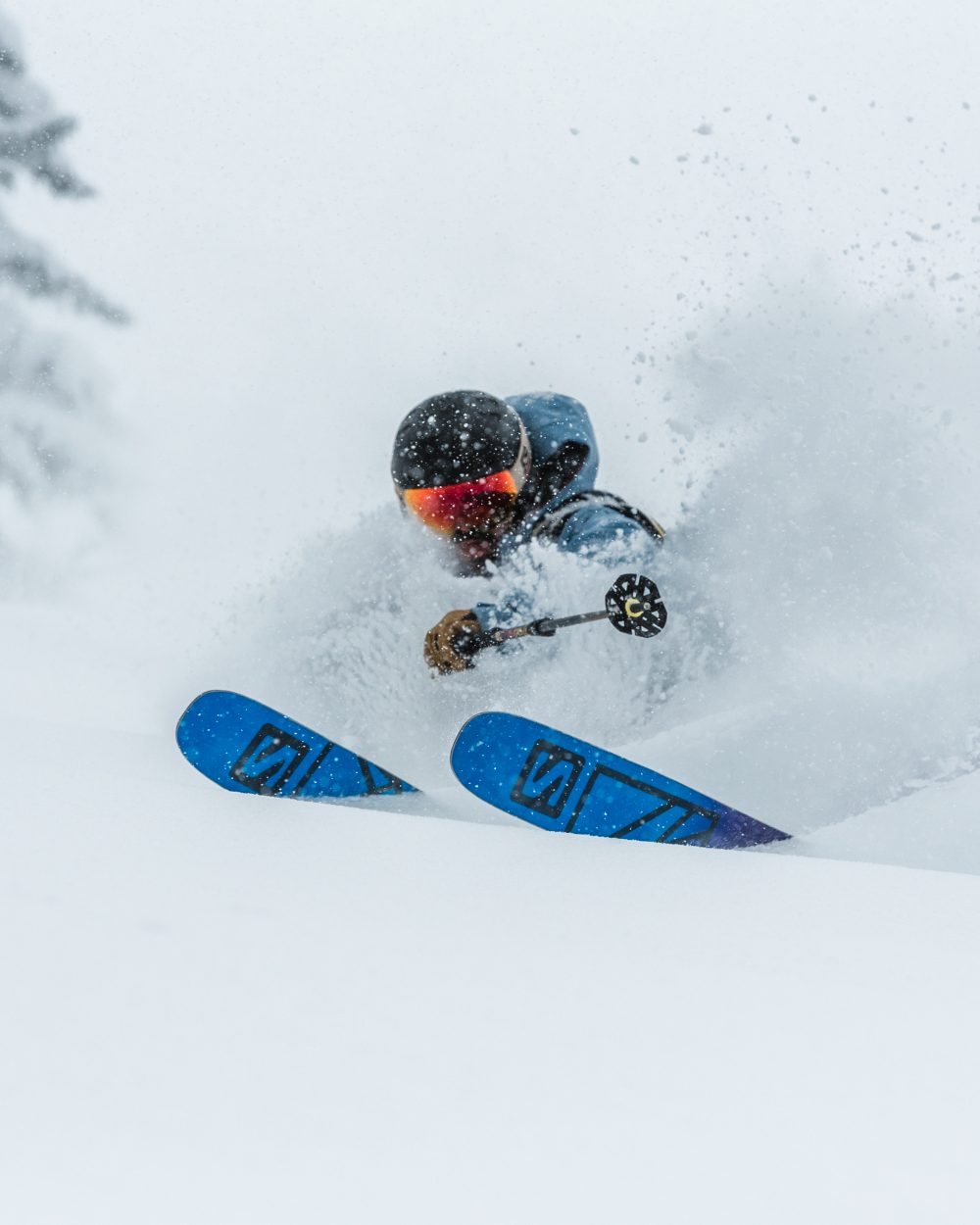 A person skiing down a snow covered slope in deep snow. Salomon QST Blank Ski commercial picture. Shot in Airolo Switzerland.