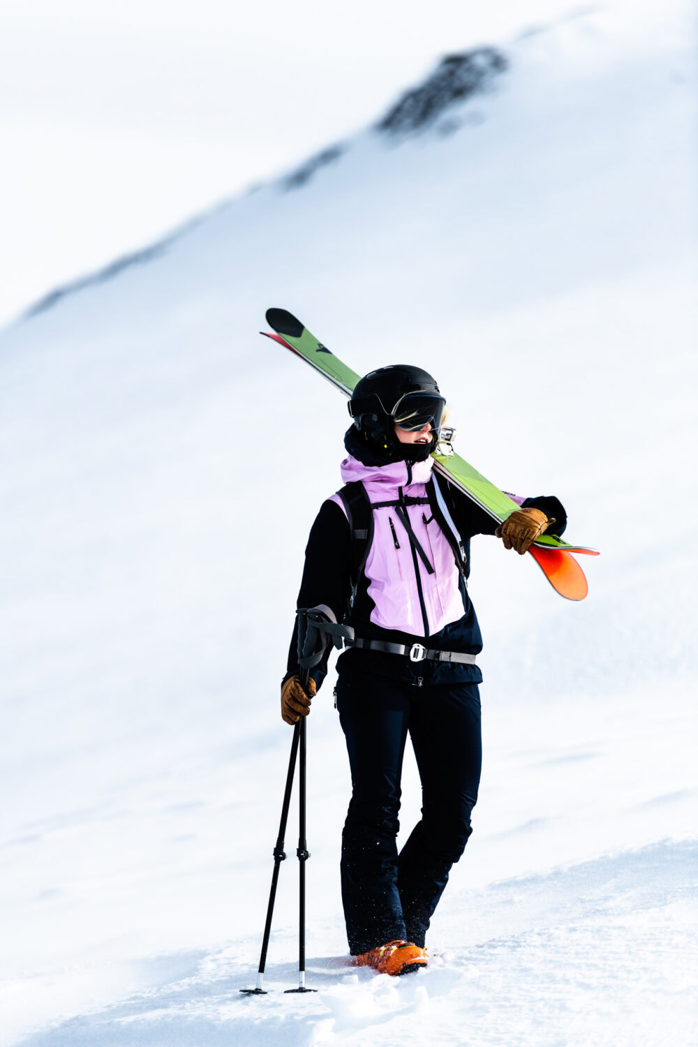 A person walking up a hill with skis and poles. J.Lindeberg Ski fall/winter 21. Campaign photographed by Axel Adolfsson.