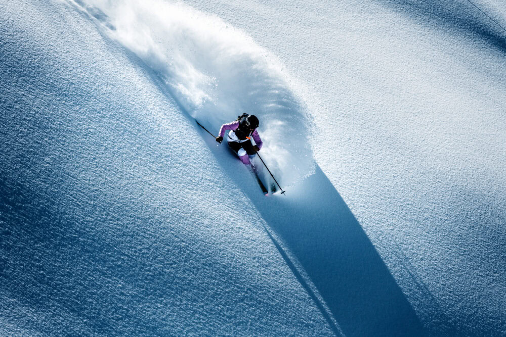 A person skiing down a snow covered slope. J.Lindeberg Ski fall/winter 21. Campaign photographed by Axel Adolfsson.