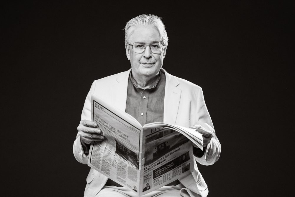 Sophisticated black and white portrait of an elderly man in glasses reading a newspaper, high contrast photography by Axel Adolfsson.