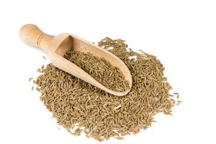 Cumin seeds in a spoon for spices isolated on a white background