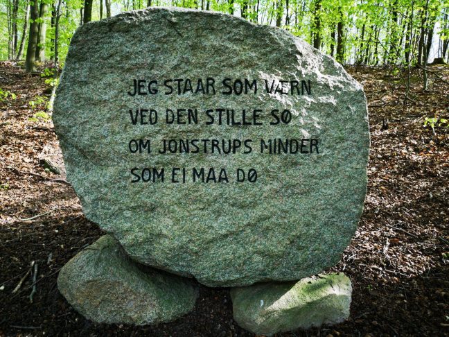 Mindesten i skoven, med tekst: "Jeg Staar som værn ved den stille sø om Jonstrups minder som Ei maa dø"