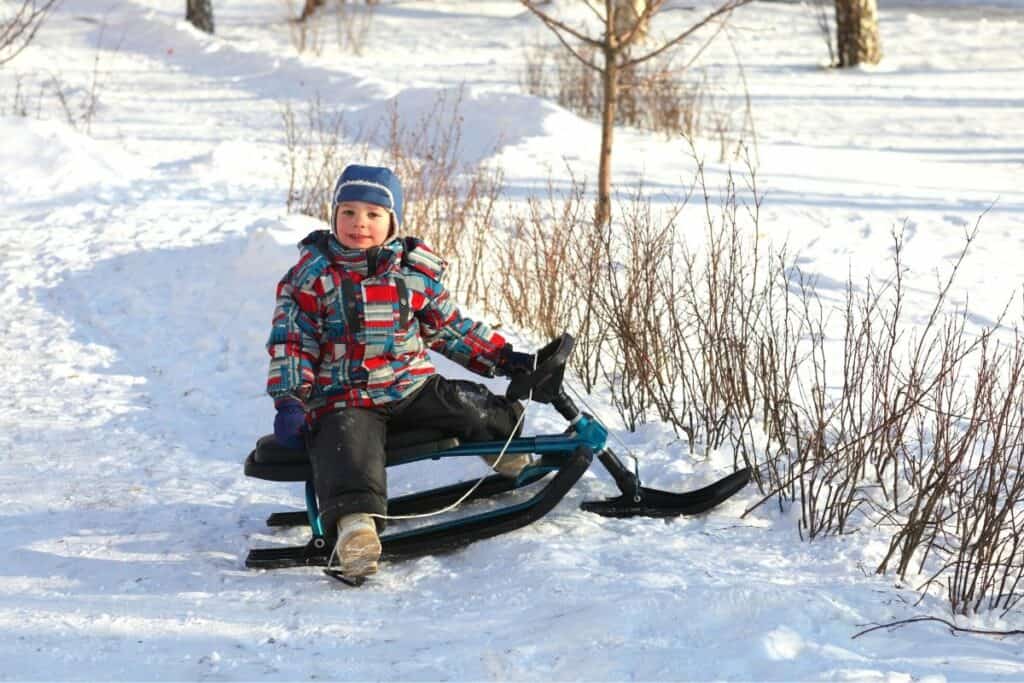 Barn sitter på en rattkjelke i snøen