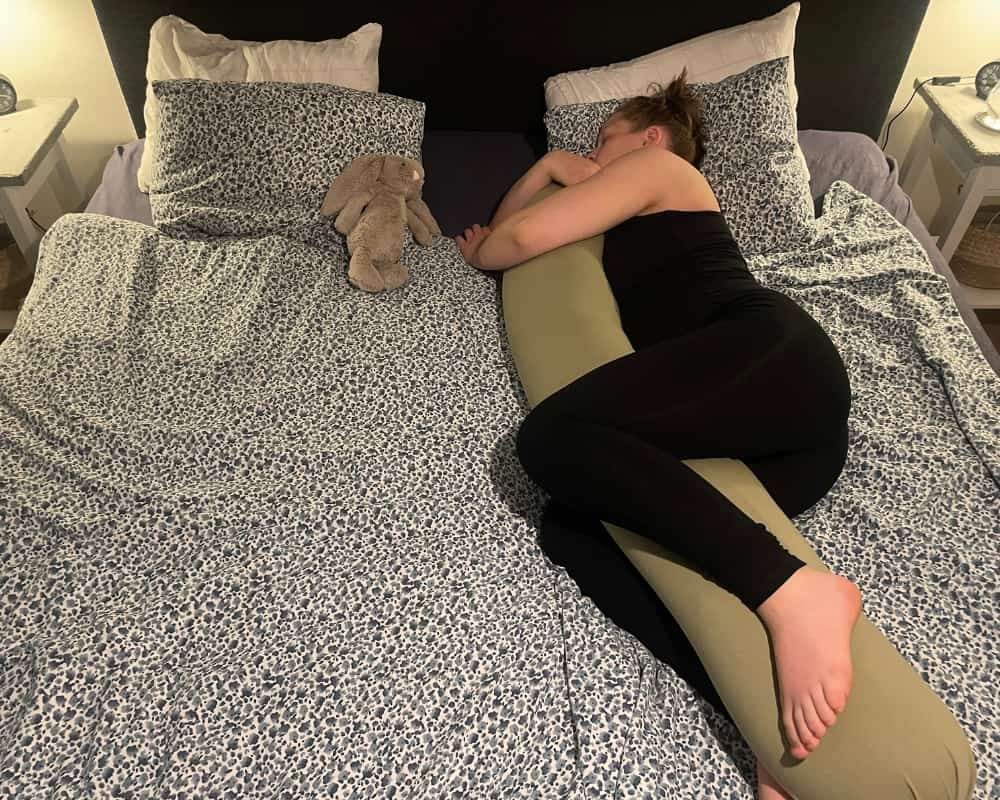 Kvinne ligger i sengen med Najell graviditetspute
