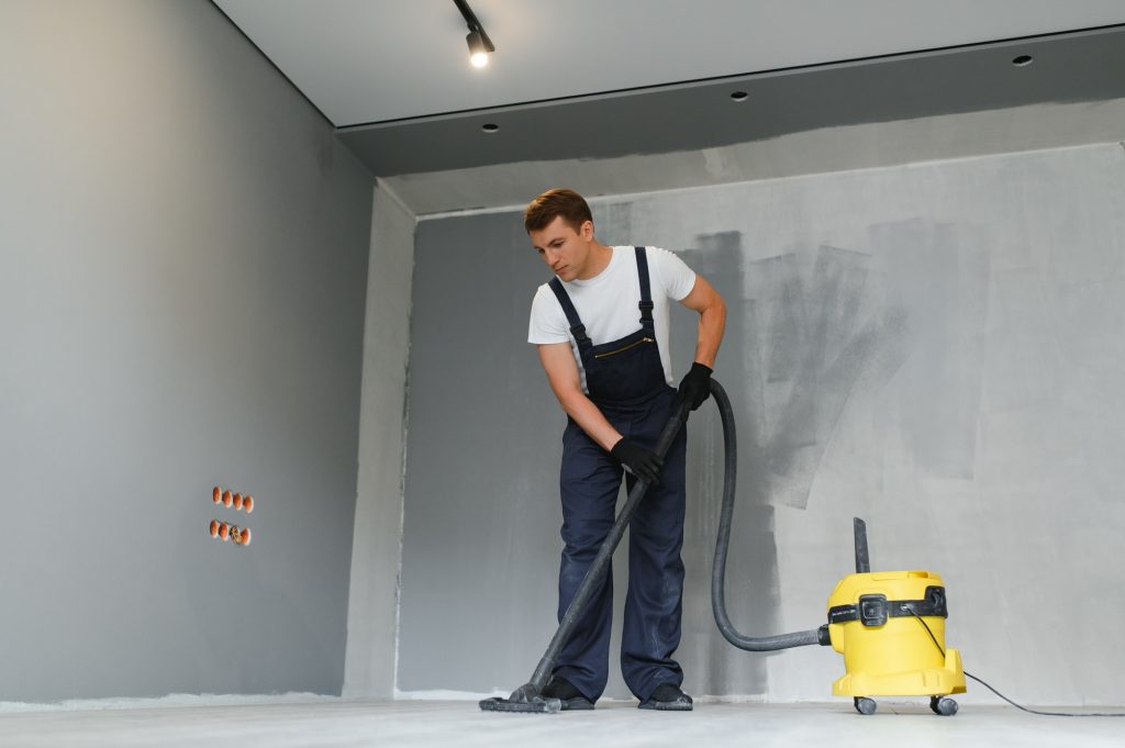 A worker vacuums a room after repairing the floors. Apartment after renovation with a vacuum cleaner