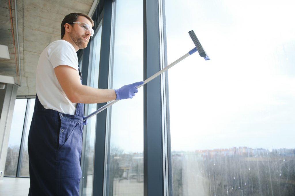 Male worker washing window glass