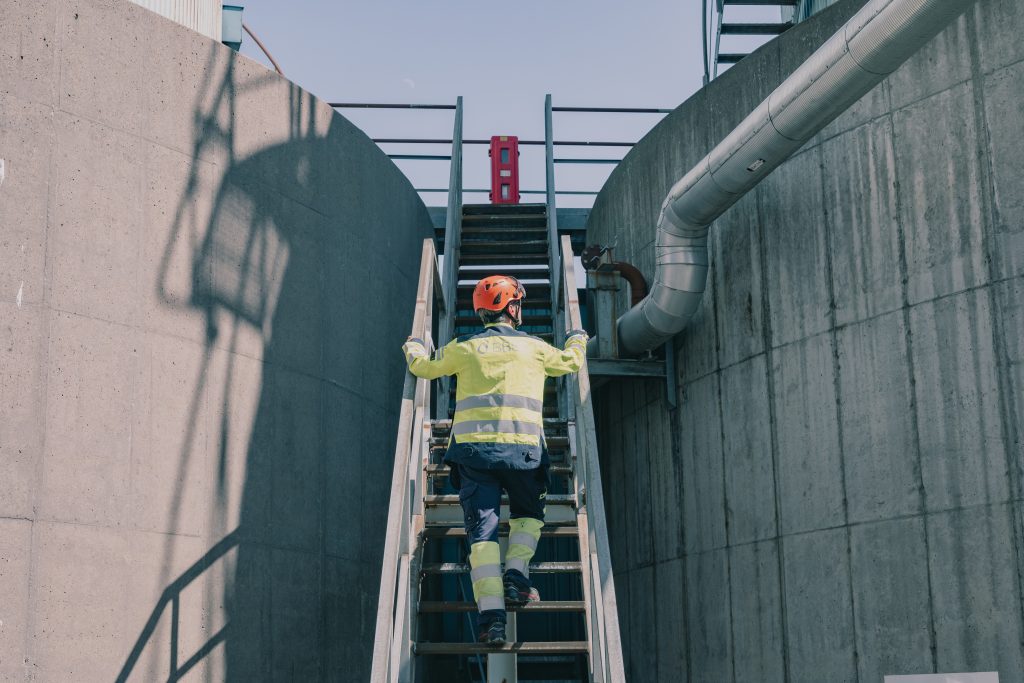 Industrial worker standing on stairs by cistern.