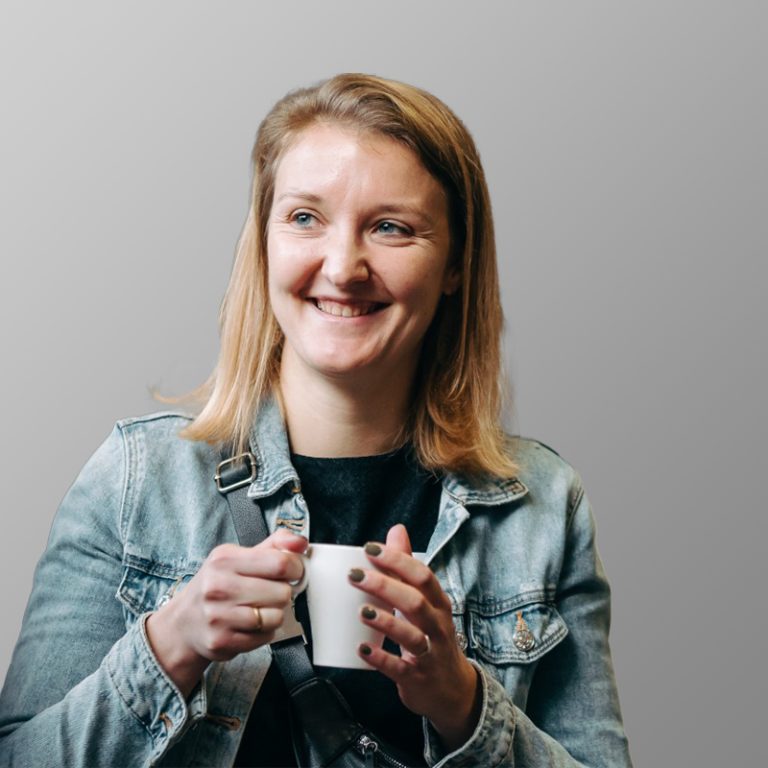Lotte Verheyen, Developer & Ondersteuning bij BeLoWeb, lachend met een kopje koffie.