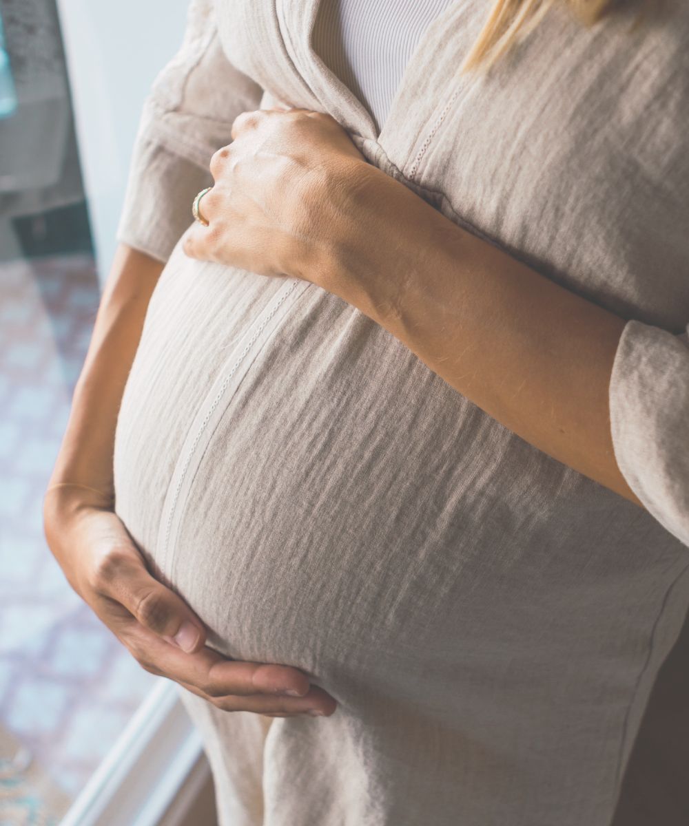 a woman holding her pregnant belly with mindful care