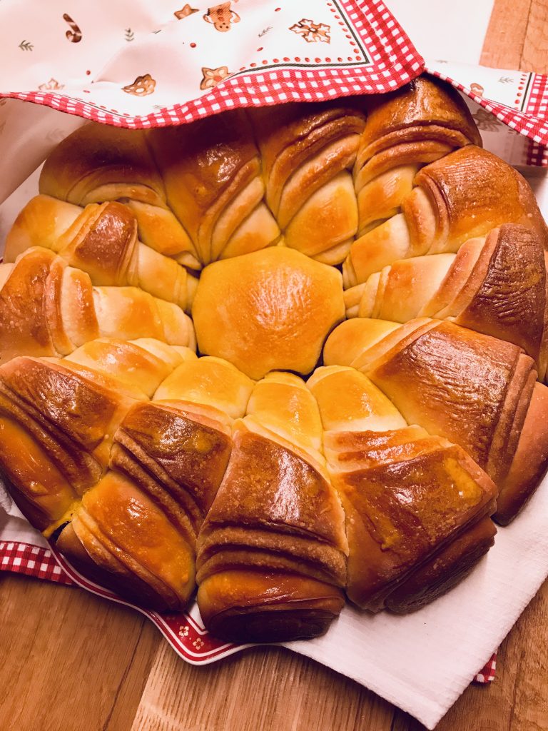 Ritual Bulgarian bread with a golden crust, beautifully lit by soft, warm light, resting on a festive table decorated for Christmas.