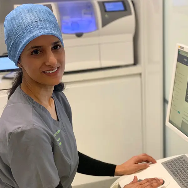 The dentist Aadila Peer in her office practising at Bicester Dental. She is smiling to the camera in her dental clothing.