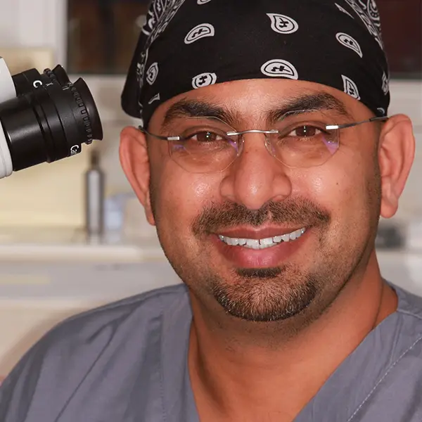 The Dentist Ashruf Peer smiling at the camera from his dental office in Bicester Dental