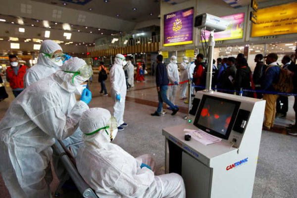 Medical staff in protective gear look at a screen while checking temperatures of passengers upon their arrival, following an outbreak of the coronavirus, at Najaf airport, in the holy city of Najaf