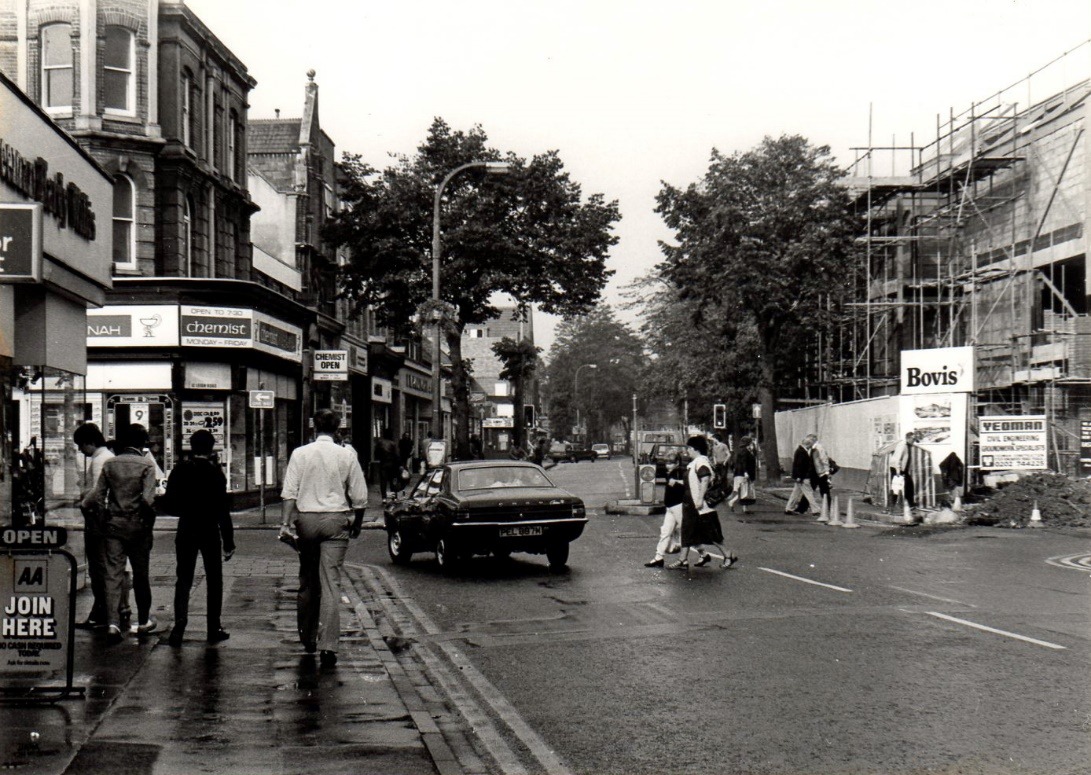 A black and white photo of a busy street with people and cars Description automatically generated with medium confidence