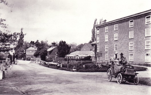 A black and white photo of a horse drawn carriage on a dirt road Description automatically generated with low confidence