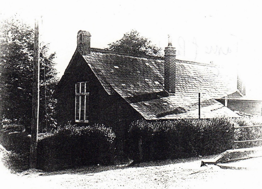 A black and white photo of a house with a chimney and bushes Description automatically generated with low confidence