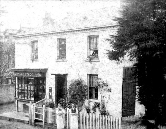 A black and white photo of a house with a couple of people standing in front of it Description automatically generated with low confidence